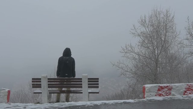 Man sitting on a bench, standing and walking away