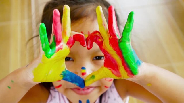 Close up of Asian girl making a heart sign with colourful painting her hand, slow motion shot 100 fps