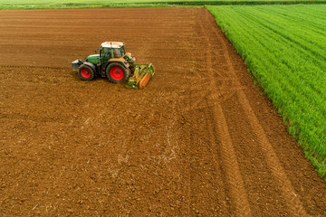 Aerial shot of  Farmer with a tractor on the agricultural field sowing.