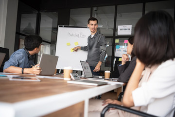 Group of young modern people in casual wear planning business strategy. Business team analyzing income charts and graphs. Setup studio shooting.