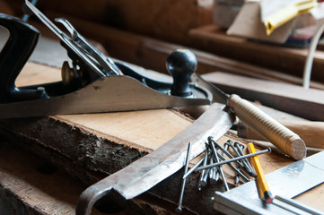 Carpentry tools in on wood boards in a little workshop, focus on the nails.