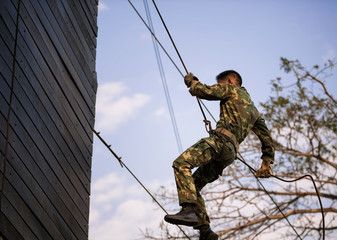 Soldier training rappel with rope. Military man does hanging on climbing equipment.