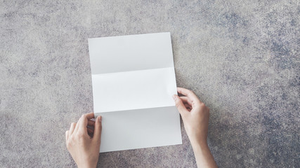Female hands holding blank white folded paper on background