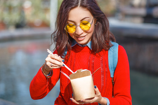 Asian Woman eating street food from takeaway paper box outdoors in Hong Kong
