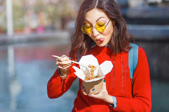 Asian Woman eating street food from takeaway paper box outdoors in Hong Kong