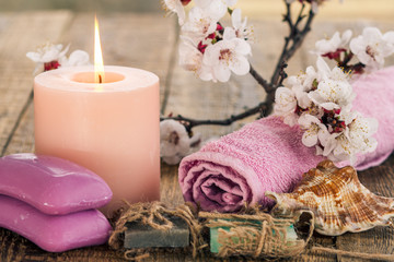 Obraz na płótnie Canvas Soap with rolled towel, sea shell and burning candle with flowering branch of apricot tree