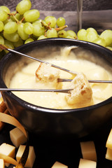 Gourmet Swiss fondue dinner on a winter evening with assorted cheeses on a board alongside a heated pot of cheese fondue