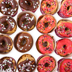 Colorful homemade donuts flat lay on white background, top view