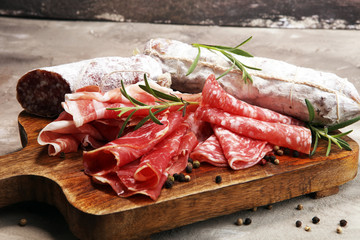 Food tray with delicious salami, prosciutto crudo,  fresh sausages and herbs. Meat platter with selection
