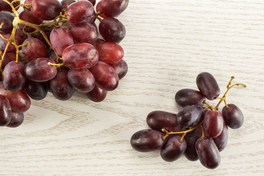 Two red globe grape clusters table top isolated on grey wood background dark pink berries