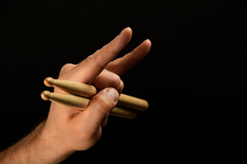 Man hand with drumsticks and devil horns on black