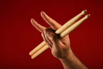Man hand with drumsticks and devil horns on red