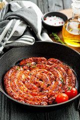Barbecue sausages in frying pan on wooden table. 