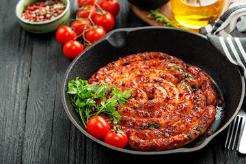 Barbecue sausages in frying pan on wooden table. 