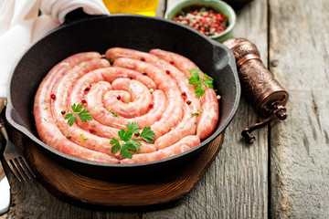 Raw sausage of beef and pork with spices on dark wooden background. 