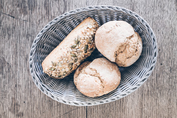 top view of basket with German style bread rolls on old rustic wooden table