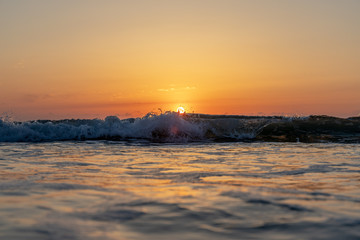 Fototapeta na wymiar Sunset with waves splashing in foreground
