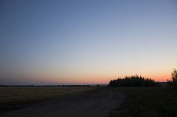 Sundown and sunrises. bright night. dark blue sky with tints of orange, red, yellow and much clouds. Silhouettes of forests far away on the background of heaven