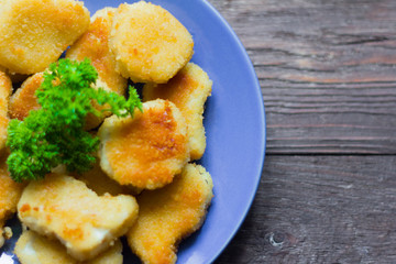 chicken nuggets fried to Golden brown with parsley on wooden background
