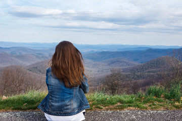 Naklejka premium Woman traveler sits and looks at the mountains