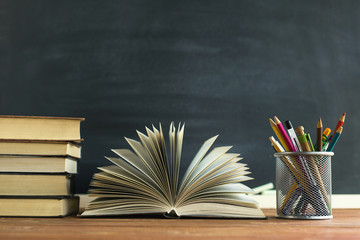 Textbooks and school supplies on a table, against a chalkboard background with chalk. Concept of...