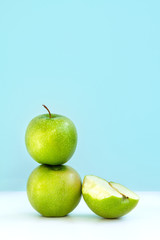 one green Apple on another and next half bitten Apple on blue background