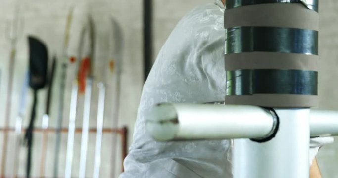 Kung fu fighter practicing martial arts with wooden dummy 