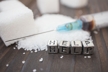 syringe, white sugar and inscription-help on a wooden background, concept of diabetes