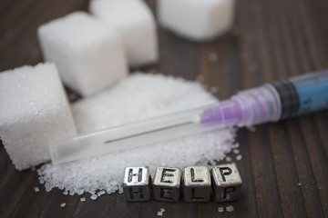 syringe, white sugar and inscription-help on a wooden background, concept of diabetes