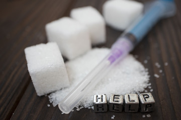 syringe, white sugar and inscription-help on a wooden background, concept of diabetes