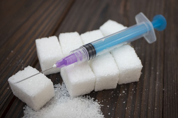 syringe and white sugar on wooden background, concept of diabetes