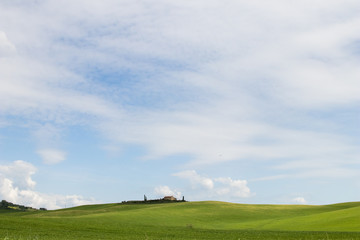 Italian landscape with green fields in spring, holidays in Italy in Umbria and Tuscany. Travel drive in the Tuscany countryside with soft green hills and blue skies. Calm and relax holidays in Italy