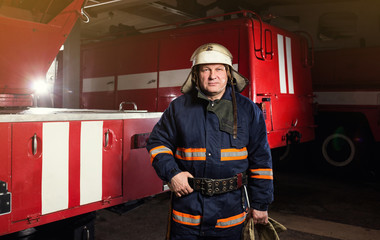 Fireman (firefighter) in action standing  near a firetruck. Emergency safety. Protection, rescue from danger.