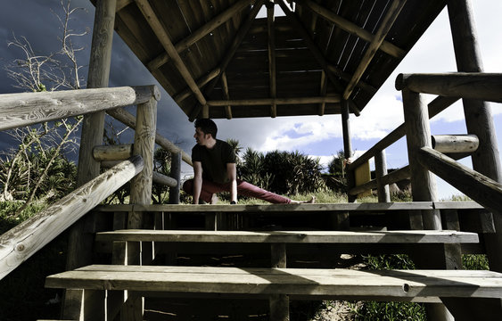Chico joven realizando estiramientos de yoga en la caba&ntilde;a de madera