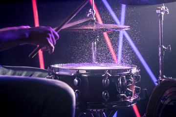 the man plays the drums, on the background of colored lights