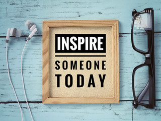 Motivational and inspirational quote - ‘Inspire someone today’ written on a framed paper. With...