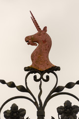 red metal unicorn crest with dual spiral horns on wrought iron decoration