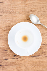top white coffee cup with coffee stains next to spoon and on wooden background