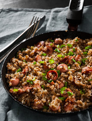 Fried Meat sausages in a frying pan with buckwheat porridge on dark wooden table
