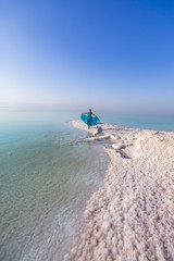 Fototapeta premium Blonde young woman in a blue dress on the shore of the dead sea. Jordan