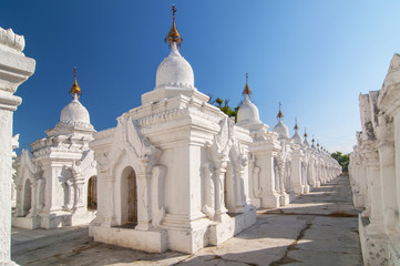 Fototapeta na wymiar Kuthodaw Pagoda contains the worlds biggest book. There are 729 white stupas with caves with a marble slab inside page with buddhist inscription. Mandalay, Myanmar.