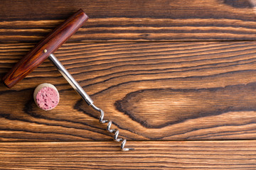 Corkscrew with cork against wooden background