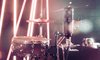 The microphone in a recording Studio or a concert hall close up of drum kit and an acoustic guitar in the background.