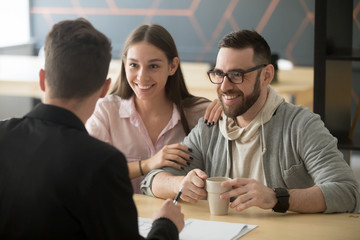 Realtor, bank worker, insurance broker or financial advisor consulting smiling millennial couple,...