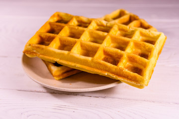 Ceramic plate with belgian waffles on wooden table