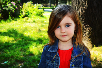 Naklejka premium Bellisima felice bambina con occhi azzuri nel parco verde