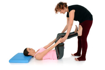 Obraz premium Yoga teacher helping young girl to do yoga