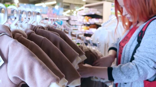 Woman Chooses Clothes for Child at Supermarket.
