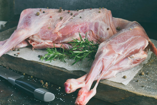 Whole raw lamb and knife on the wooden board. Sheep carcass with fresh herbs, spices. Raw meat. Free space for text.