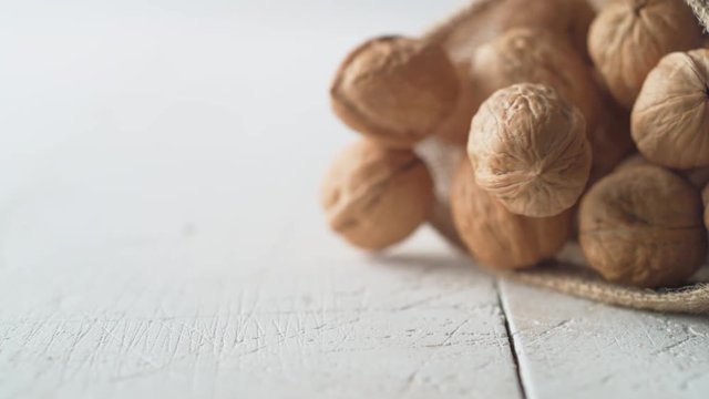 Walnuts in shell rolling out of burlap bag. Shot with high speed camera, phantom flex 4K. Slow Motion.